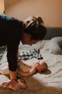 Moeder praat met haar baby op bed – vroege taalontwikkeling en zorg voor een gezonde start